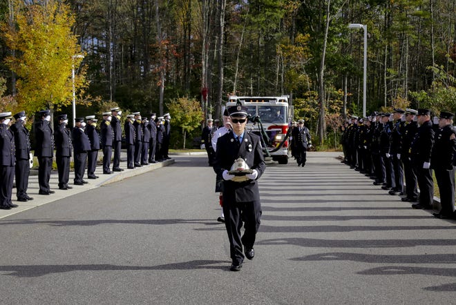 Grandson Bradley Gorman carries Fire Chief George Gorman's helmet through a line of firefighters Friday morning before the funeral in South Berwick, Maine. [ Shawn St. Hilaire/Fosters.com]