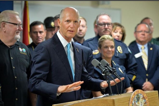 Gov. Rick Scott is surrounded by law enforcement officials at the Bradenton Police Department in September as he announces a plan to push for legislation to fight opioid abuse. (File photo/Mike Lang)