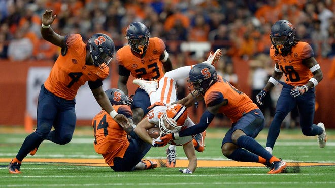 Clemson wide receiver Hunter Renfrow (13) is upended by Syracuse defensive back Evan Foster (14) and defensive back Jordan Martin (2) during the first half. [The Associated Press]