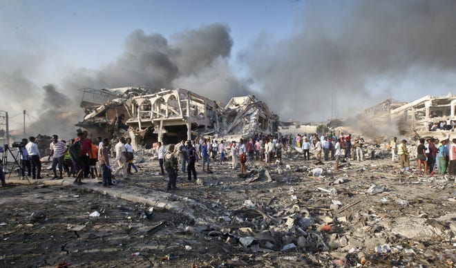 Somalis gather and search for survivors by destroyed buildings at the scene of a blast in the capital Mogadishu, Somalia, Saturday, Oct. 14, 2017. A huge explosion from a truck bomb has killed at least 20 people in Somalia's capital, police said Saturday, as shaken residents called it the most powerful blast they'd heard in years. (AP Photo/Farah Abdi Warsameh)