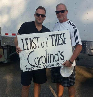 Contemporary Christian singer-songwriter Matthew West, left, and Craig Barnwell of Emporia, Kansas, hold up a sign paying tribute to Gastonia-based Least of These Carolinas, prior to a recent concert. [Special to The Gazette]