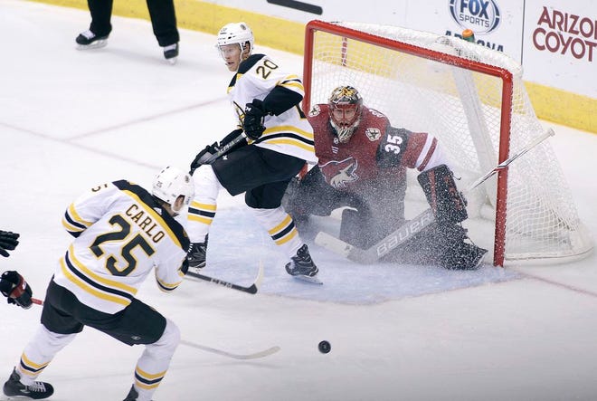 Arizona Coyotes goalie Louis Domingue (35) positions himself for a save on the shot by Boston Bruins' Brandon Carlo (25) as Bruins' Riley Nash skates through the crease during the second period. [The Associated Press]