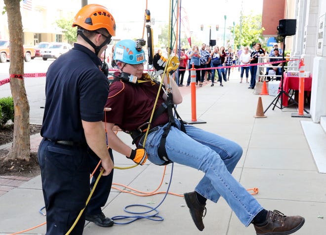 Fort Smith Firefighter Brian Edwards helps Keenan Adkins, Propack director of IT, recovers from his go "over the edge" Friday, Oct. 13, 2017, during the 2nd annual Over The Edge Challenge down the face of the First National Bank at 6th and Garrison Ave. Ten sponsors made the decent from the top of the bank to 108 feet below during the first day of the 26th annual Survivors' Challenge Weekend to benefit the Donald W. Reynolds Cancer Support House. The event includes the Survivors' Challenge Arkansas Grand Prix Series 10K Race, 5K USTAF Certified Run and Celebration Walk starting from Reynolds Cancer Support House, 3324 South M Street at 8 a.m. Saturday, Oct. 14, 2017. The Over The Edge Challenge continues Saturday, Oct. 14, 2017, at 9 a.m., with more than 60 rappelers lined up to make the step over the edge. [JAMIE MITCHELL/TIMES RECORD]