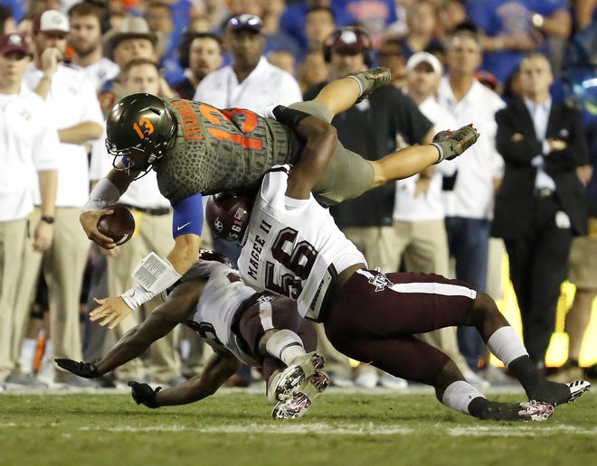 Florida quarterback Feleipe Franks is upended by Teaxs A&M defenders Saturday night at Ben Hill Griffin Stadium. [Brad McClenny/Staff photographer]