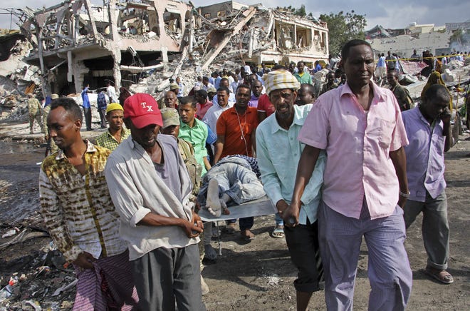 Somalis remove the body of a man killed in Saturday's blast, in Mogadishu, Somalia Sunday, Oct. 15, 2017. The death toll from the huge truck bomb blast in Somalia's capital rose to over 50 Sunday, with more than 60 others injured, as hospitals struggled to cope with the high number of casualties, security and medical sources said. (AP Photo/Farah Abdi Warsameh)