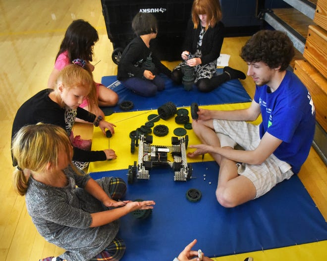 Members of a robotics club from UNH called UNH STEMbassadors spent time with students who read over 1,000 minutes over the summer at Idlehurst Elementary School in Somersworth. Here, Ethan Stewart helps second graders assemble wheels and gears for robots. Students also were challenged in teams to create roller-coasters with various materials. 
[Deb Cram/Fosters.com]