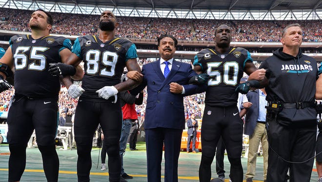 Jacksonville Jaguars team owner Shad Khan (center) and head coach Doug Marrone stand united arm-in-arm with players Brandon Linder (65) Marcedes Lewis (89) and Telvin Smith (50) on the sideline during the singing of the American national anthem before kick-off against the Baltimore Ravens in an NFL game Sept. 24 in London. (Rick Wilson/Jacksonville Jaguars)