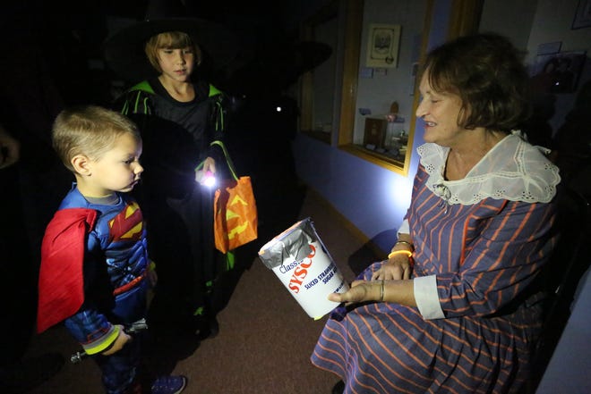 Joanne Wiegert, playing Miss Vada Watson, the Kansas Wheat Queen, offers Clay Brooks, 3, and Sidney, 8, to feel her bucket of wheat during the 2015 spook walk, which returns tonight at the Reno County Museum.