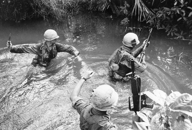 Soldiers of the U.S. 25th infantry division wade through a canal in pursuit of a Viet Cong sniper who opened fire on them during mission west of Cu Chi near South Vietnamese border with Cambodia on Aug. 12, 1967. [AP PHOTO, FILE]