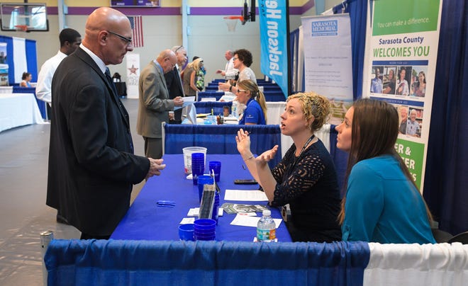 Ed Johnson of Venice talks about county jobs with Erin Lee, center, and Hannah Hunt during a job fair at Robert L. Taylor Community Center in Sarasota on Tuesday. Hundreds of job seekers were able to meet with about 40 local companies to explore employment opportunities. The fair was presented by CareerSource Suncoast and the Herald-Tribune Media Group.  [Herald-Tribune staff photos / Dan Wagner]