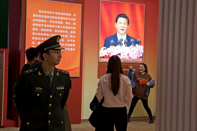A visitor poses near a photo of Chinese President Xi Jinping at an exhibition highlighting China's achievements under five years of Xi's leadership at the Beijing Exhibition Hall in Beijing, China, Tuesday, Oct. 17, 2017. Having bested his rivals, Chinese President Xi Jinping is primed to consolidate his already considerable power as the ruling Communist Party begins its twice-a-decade national congress on Wednesday.(AP Photo/Ng Han Guan)