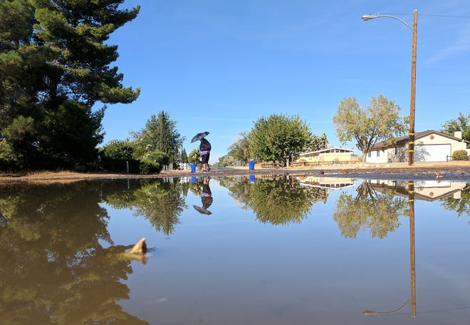 A resident walks through a flooded section near Sitting Bull and Kiowa roads in Apple Valley early Tuesday morning. A water main broke and flooded sections of the area. [James Quigg, Daily Press]