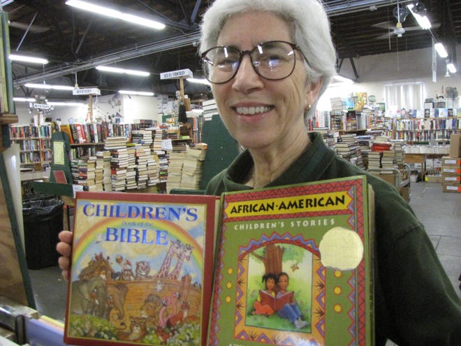 Ellen Smith, a member of the Friends of the Library who volunteers at the book house, dislays the “Children’s Bible” and the “African-American Children’s Stories,” both of which will be available in the children’s area during the Fall Book Sale, which will run Saturday through Wednesday. [Aida Mallard/Correspondent]