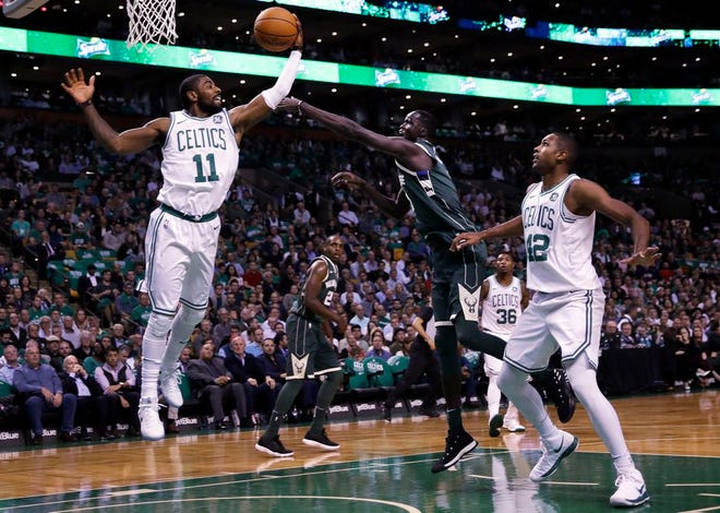 Boston Celtics guard Kyrie Irving, left, grabs a rebound against Milwaukee Bucks forward Thon Maker, center, during the first quarter of an NBA basketball game, Wednesday, Oct. 18, 2017, in Boston. At right is Boston Celtics center Al Horford.
