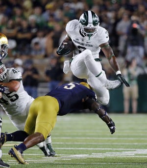 FILE - In this Sept. 17, 2016, file photo, Michigan State running back LJ Scott (3) carries the ball and hurdles Notre Dame linebacker Nyles Morgan (5) during the first half of an NCAA college football game in South Bend, Ind. (AP Photo/Charles Rex Arbogast, File)