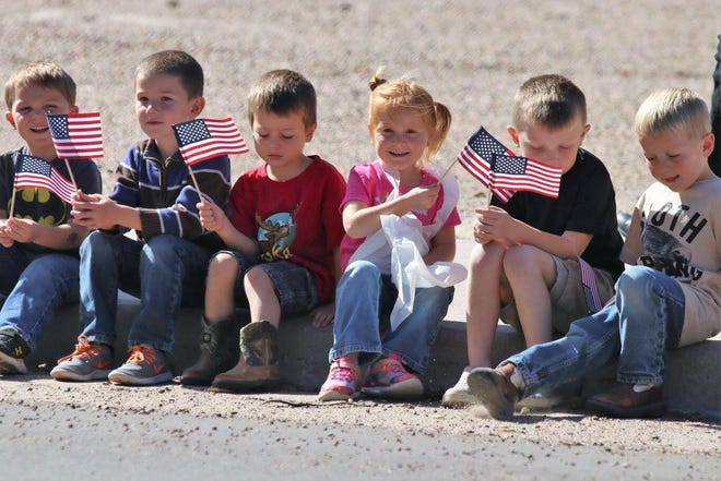 Oakley elementary students Mac Glaze, Brevan Leitner, Carson Kincaid, Kailey Lauber, Channing Crotts and Gage Lauber line the curb to watch the arrival of the 9/11 NEVER FORGET Mobile Exhibit in Oakley Tuesday. [COURTESY PHOTO]