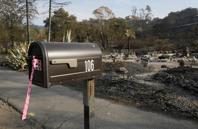 FILE - In this Oct. 16, 2017 file photo, a mailbox, one of few items left at the site of the destroyed home in Napa, Calif., where Sara and Charles Rippey died in a fast-moving wildfire, shows a pink and black polka dot ribbon that indicates a fire crew has visited the location. The vast majority of those who died in the Northern California wildfires were in their 70s and 80s including several couples who died together. (AP Photo/Eric Risberg)