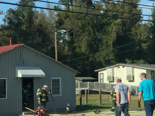 Fire fighters are seen exiting a building on N.C. 55 after extinguishing a fire. [Gwen Sutton/Contributed photo]