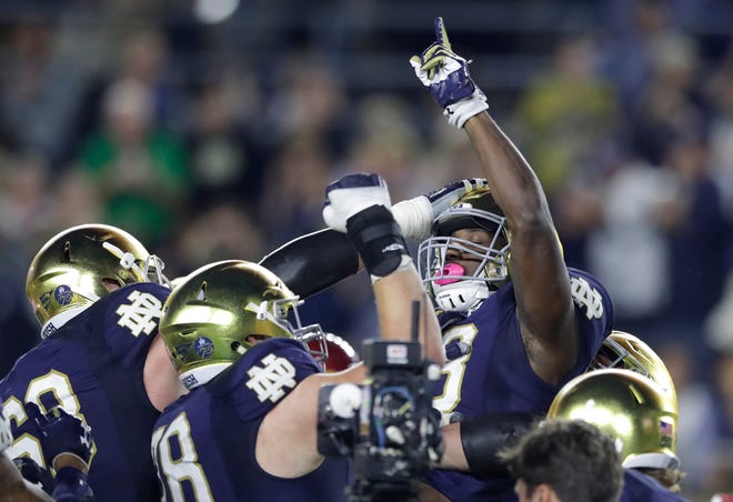 Notre Dame running back Josh Adams points skyward while lifted by teammates after one of his three touchdowns in an NCAA college football game against Southern California, Saturday, Oct. 21, 2017, in South Bend, Ind. (AP Photo/Carlos Osorio)