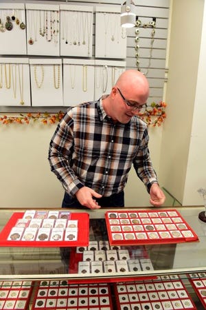 Ted Brigante looks at a collection of Morgan silver dollars for sale at E&B Co. in Moorestown on Oct. 17. Brigante is one of the store owners, which sells coins and other items. [CARL KOSOLA / STAFF PHOTOJOURNALIST]