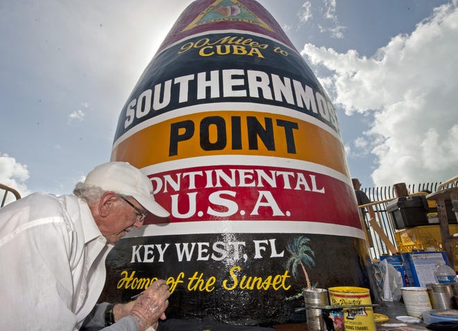 In this photo provided by the Florida Keys News Bureau, artist Danny Acosta completes lettering the Southernmost Point in the Continental U.S.A. marker Monday in Key West. [Rob O'Neal/Florida Keys News Bureau via AP]