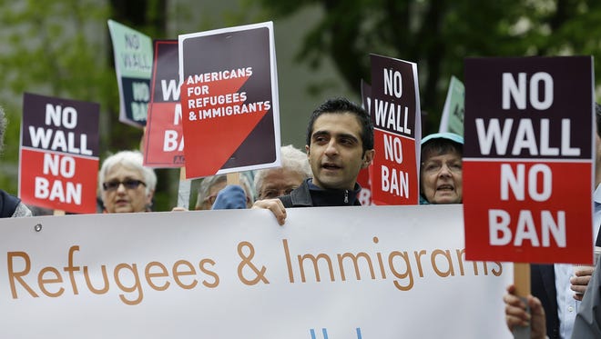 FILE--In this May 15, 2017, file photo, protesters hold signs during a demonstration against President Donald Trump's revised travel ban, Monday, May 15, 2017, outside a federal courthouse in Seattle. TrumpþÄôs six-month worldwide ban on refugees entering the United States is ending as his administration prepares to unveil new screening procedures. A State Department official says the suspension of processing for refugees ended Tuesday, the date set in TrumpþÄôs executive order. (AP Photo/Ted S. Warren, file)