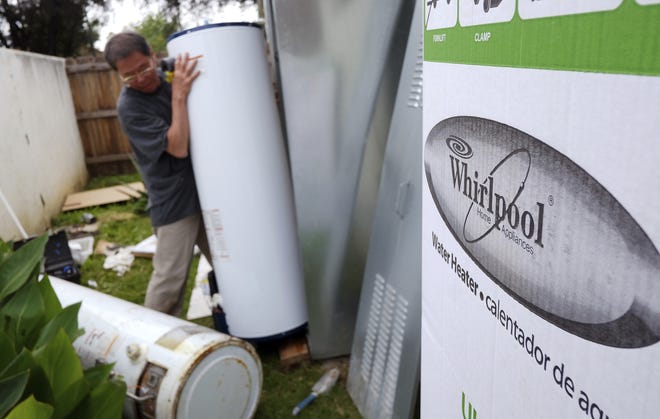 In this Sunday, March 22, 2015, file photo, a repairman installs a Whirlpool water heater at a home in Los Angeles. Sears will no longer sell Whirlpool appliances, ending a business partnership that dates make more than 100 years. (AP Photo/Richard Vogel, File)