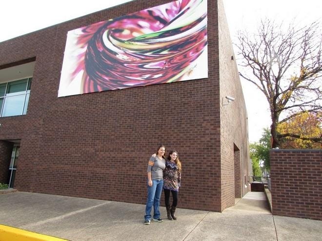 SHARON WOODS HARRIS/GATEHOUSE MEDIA ILLINOIS Project Photographer Rebecca Richardson and Jeremie Draper, a soft glass artist and owner of J. Draper Glass, revel Monday in the display of a mural of one of the 2017 Series, "Watermelon Tourmaline Pumpkin" at the Pekin Public Library. Library Director Jeff Brooks said the library is working to display more local art.