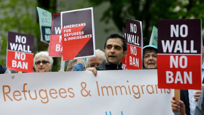 FILE--In this May 15, 2017, file photo, protesters hold signs during a demonstration against President Donald Trump's revised travel ban, Monday, May 15, 2017, outside a federal courthouse in Seattle. Trump’s six-month worldwide ban on refugees entering the United States is ending as his administration prepares to unveil new screening procedures. A State Department official says the suspension of processing for refugees ended Tuesday, the date set in Trump’s executive order. (AP Photo/Ted S. Warren, file)