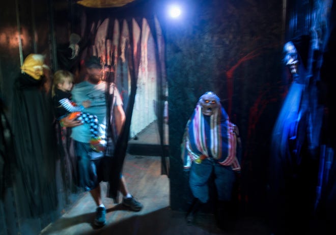 DAVID ZALAZNIK/JOURNAL STAR Emily Oleson, 4, clings to her father, Tyler, as the Prophetstown family make their way through the Hall of Horrors at Wildlife Scary Park on Saturday.
