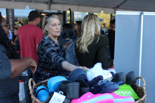 An woman makes a donation to the "Socks and Crocs for Survivors"  drive during Wednesday's grand opening of mani • pedi, which is co-sponsoring the clothing drive. (Brittini Ray/ Savannah Morning News)