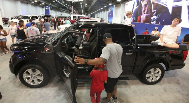 Fairgoers look at pickup trucks on display at the State Fair of Texas in Dallas. Buyers are increasingly outfitting their pickups with all the comforts of luxury cars, from heated and cooled seats to backup cameras to panoramic glass roofs. [AP Photo/LM Otero]