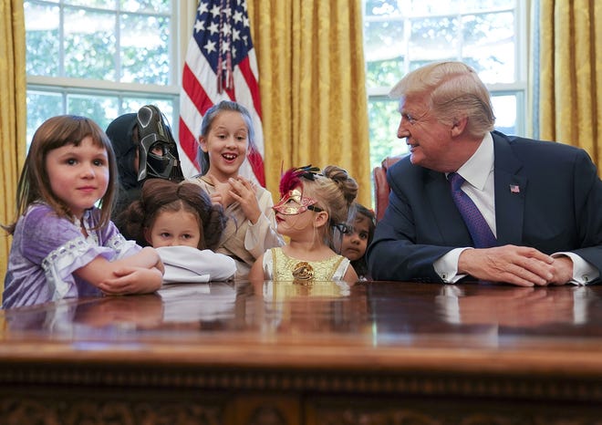 President Donald Trump meets with children dressed in their Halloween costumes in the Oval Office of the White House, Friday, Oct. 27, 2017. The White House invited the children of members of the media to visit the president and to trick-o-treat at the White House complex of the Eisenhower Executive Office building. (AP Photo/Pablo Martinez Monsivais)