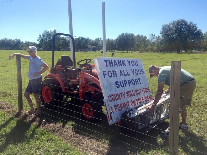 Mike and Elaine Simmons remove their pro-Trump sign from their property outside Minneola on Tuesday. [ROXANNE BROWN / DAILY COMMERCIAL]