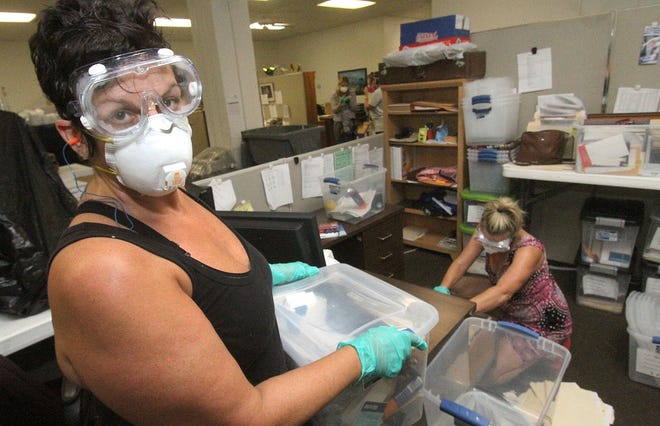 Wearing goggles, mask and gloves, MaryLou McKeon, Senior Vice President Guardianship & Client Services and guardian Amy Ballou join other employees and volunteers inside the Council on Aging on Beach Street, Monday September 18, 2017 as they pack boxes with client records and infomation, clean out their desks and move everything out to new locations following the flooding from Hurricane Irma. [News-Journal/David Tucker]