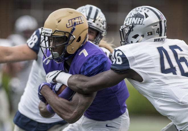 James Madison wide receiver Terrence Alls (7) squeezes through New Hampshire linebacker Jared Kuehl (58) and cornerback Prince Smith Jr. (46) during the first half of Saturday's game in Harrisonburg, Va. (Daniel Lin/Daily News-Record via AP)