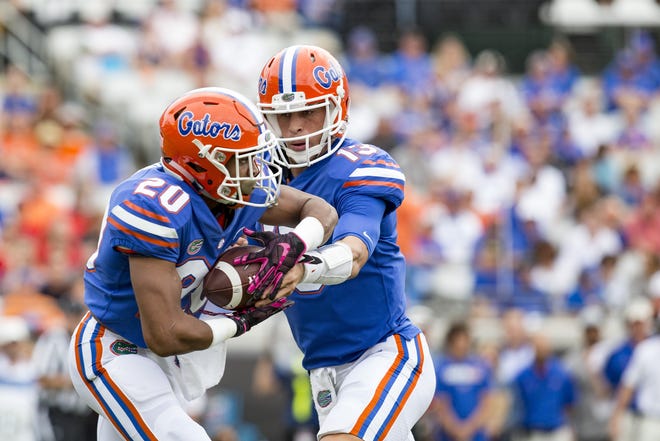Florida quarterback Feleipe Franks hands the ball to running back Malik Davis during the first quarter Saturday against Georgia. Davis suffered a knee injury and sat out most of the game. [Lauren Bacho/Special to The Sun]