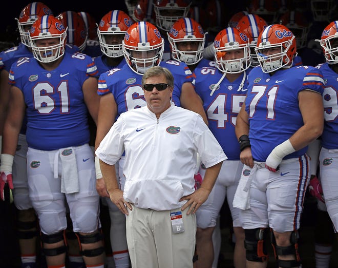 Former University of Florida head coach Jim McElwain, center, prepares to take the field with players before a game against Georgia on Saturday in Jacksonville. [John Raoux / AP]