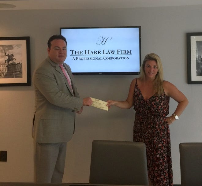 The Harr Law Firm donated $1,000 to Light the Way, a local charity that provides donations to local families with loved ones receiveing cancer treatments. Pictured from left, Attorney Jason L. Harr and Angela Heaster, who operates Light the Way. [Photo provided]