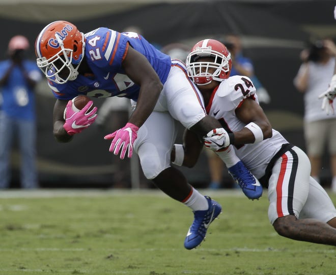 Florida running back Mark Thompson, left, is stopped by Georgia safety Dominick Sanders for a short gain Saturday in Jacksonville. [AP Photo / John Raoux]