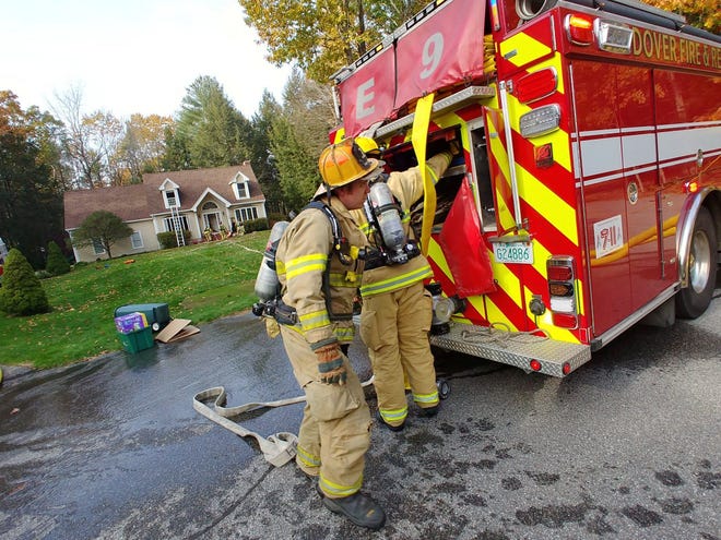 Dover firefighters work at a house fire on Quail Drive on Wednesday afternoon. Two firefighters received minor injuries when they fell through a first story floor and into the basement. [John Huff/Fosters.com]