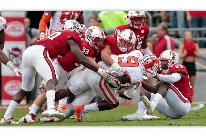 GOING DOWN — NCSU's Louis Acceus (10), Brady Bodine (33) and Shawn Boone (24) gang-tackle Clemson's Travis Etienne (9).