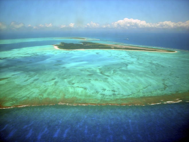 This June 2007 aerial photo shows Midway Atoll, one of the farthest in the string of the Northwestern Hawaiian Islands with long stretches of pristine atolls and coral reefs. Almost half of Hawaii's coral reefs were bleached during heat waves in 2014 and 2015, and fisheries close to shore are declining, a group of scientists told state lawmakers. [BURL BURLINGAME/AP FILE]