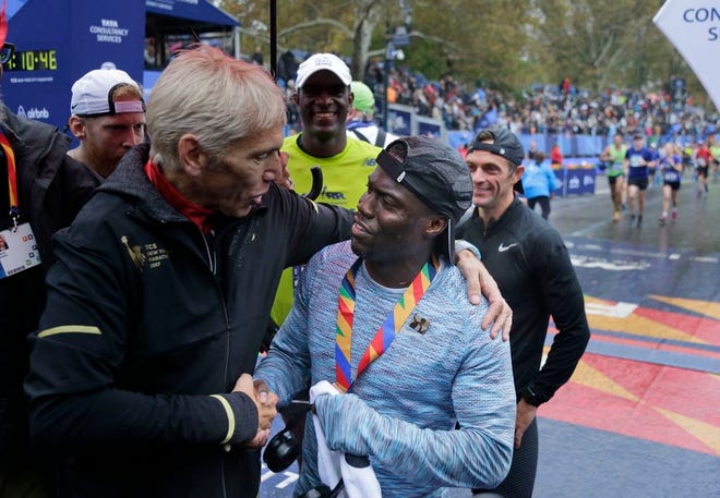 Marathon race director Peter Ciaccia, left, greets comedian Kevin Hart as he crosses the finish line of the New York City Marathon in New York, Sunday, Nov. 5, 2017. [AP Photo/Seth Wenig]