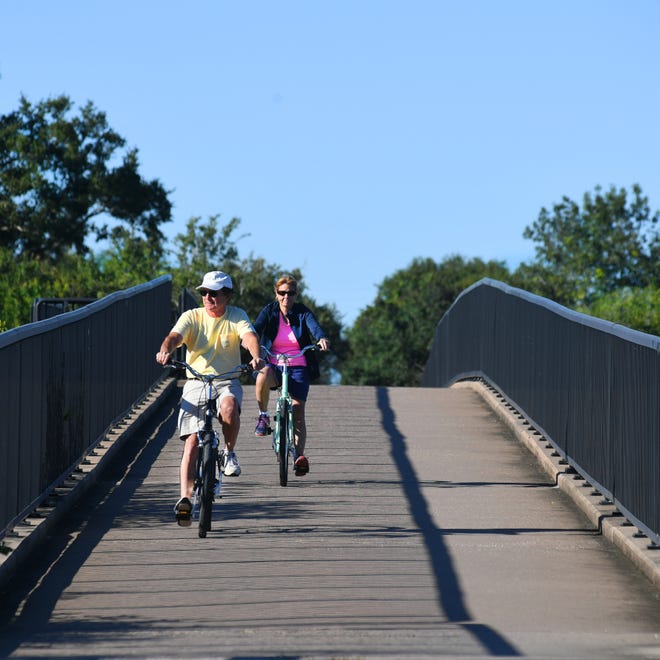Bill and Sue Newbegin ride their bikes across the Legacy Trail bridge over Dona Bay in Nokomis. The Newbegins, who recently moved to Nokomis from the Boston area, said proximiity to the Legacy Trail was part of the decision in purchasing their home. [Herald-Tribune staff photo / Mike Lang]
