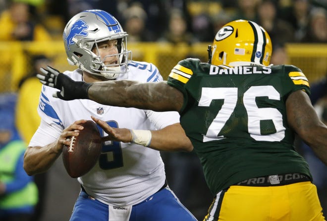 Detroit's Matthew Stafford drops back with Green Bay's Mike Daniels rushing in the first half of Monday's game. [Mike Roemer/The Associated Press]