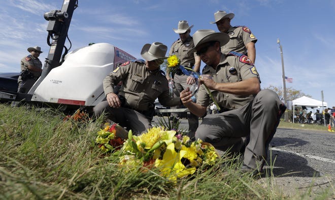 Law enforcement official move flowers left at the scene of a shooting at the First Baptist Church of Sutherland Springs, Monday, Nov. 6, 2017, in Sutherland Springs, Texas. A man opened fire inside the church in the small South Texas community on Sunday, killing and wounding many. (AP Photo/Eric Gay)