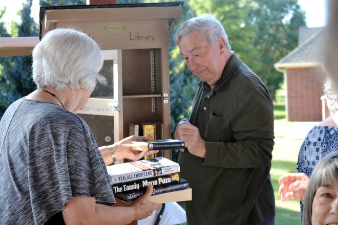 Judith Harris and Leaman Harris, both residents at Touchmark at Coffee Creek in Edmond, help install and stock books at a handmade Little Free Library in Touchmark's Parkview neighborhood. [PHOTO PROVIDED]