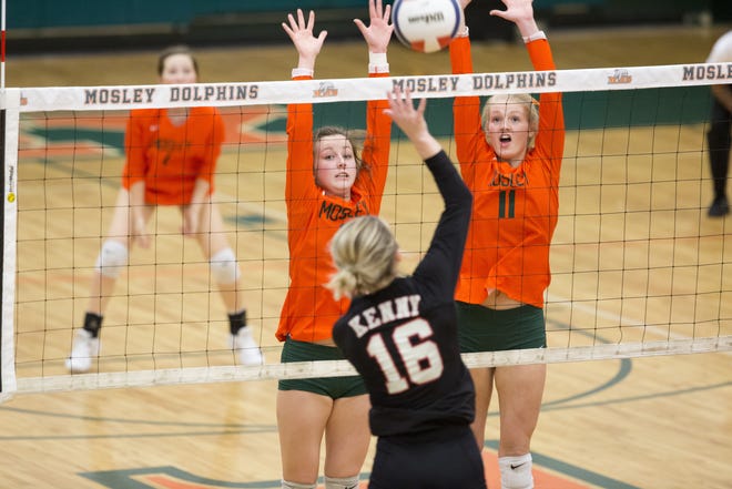 Mosley's Ragan Kinard (12) and Olivia Whittle (11) leap up to block the kill attempt by Bishop Kenny's Josephine Morrill (16) during Tuesday's match at Mosley. [JOSHUA BOUCHER/THE NEWS HERALD]