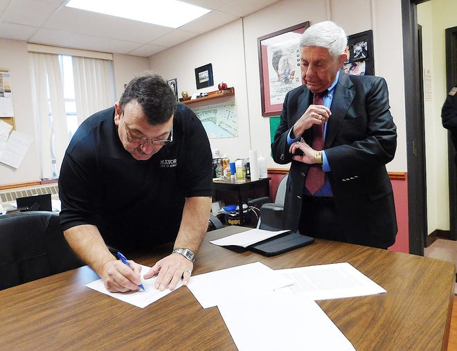 The Herkimer Village Board of Trustees unanimously approved of Mayor Tony Brindisi signing a retainer agreement with the Louis T. Brindisi Law Firm to sue opioid manufacturers and distributors for contributing to the opioid epidemic on behalf of the village. Pictured from left is Mayor Tony Brindisi signing the agreement in his office on Thursday, with Louis T. Brindisi pictured on right. [STEPHANIE SORRELL-WHITE/TIMES TELEGRAM]